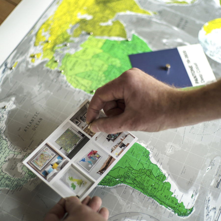 magnetic modern world map showing marked places and pinned postcards